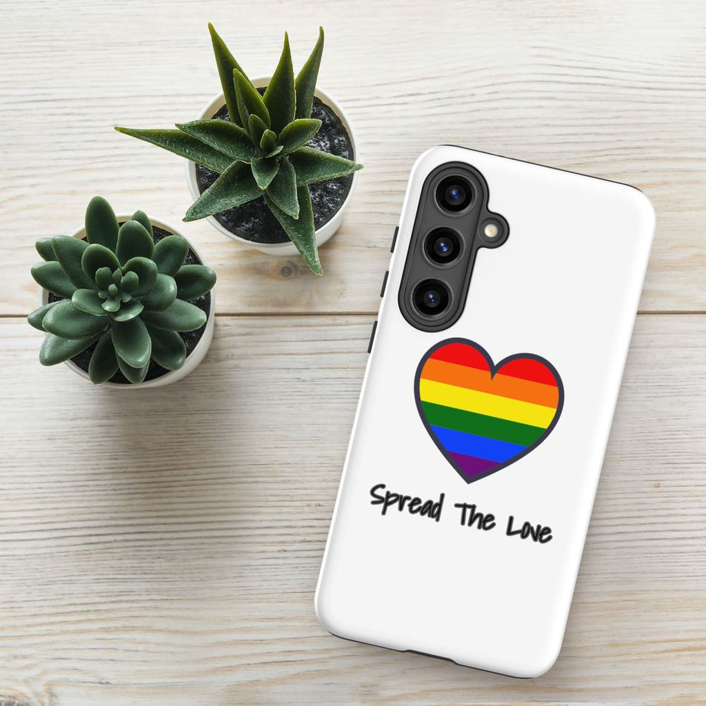 a white phone case with a heart-shaped design and the text "Spread The Love" printed on it, placed on a wooden surface alongside two potted succulent plants.