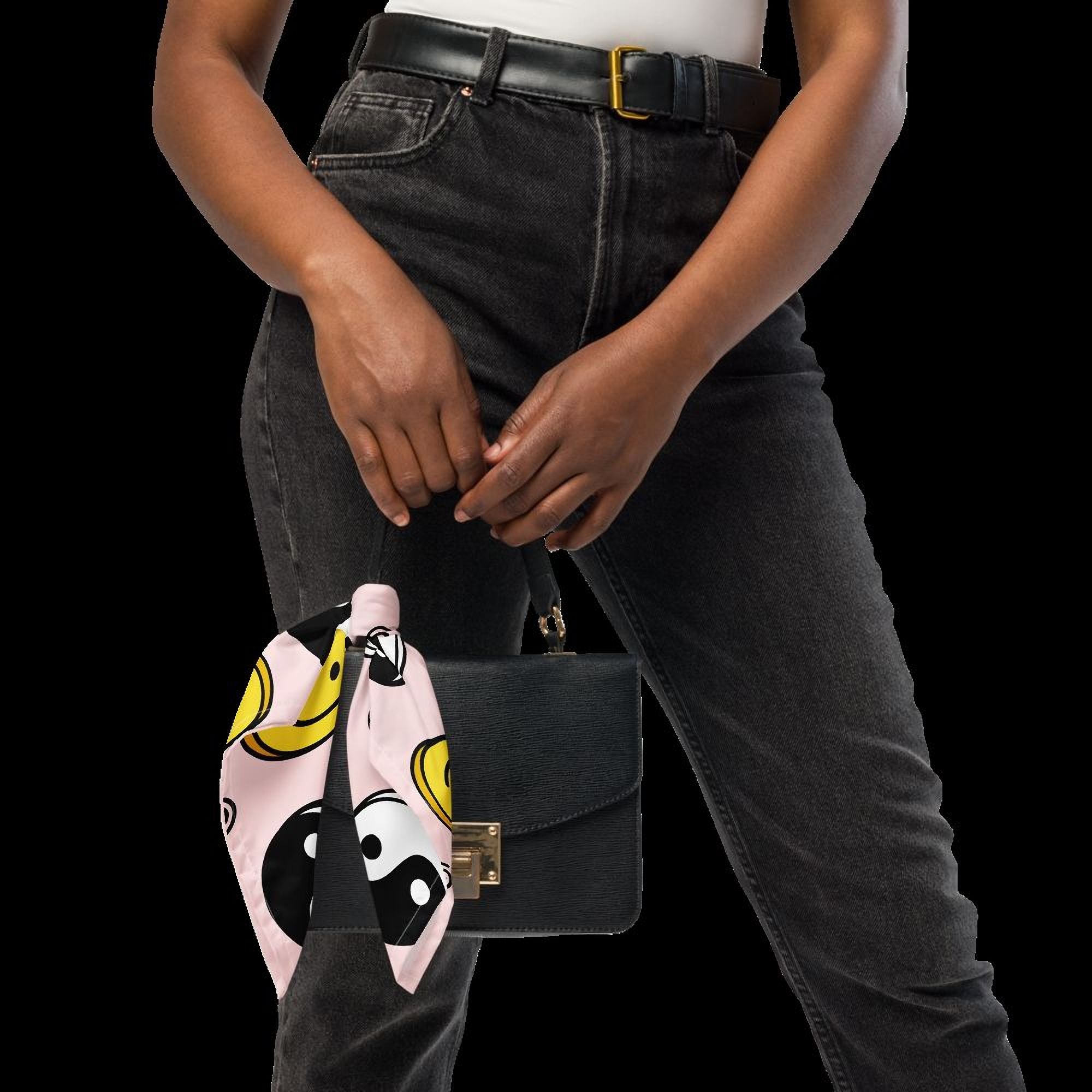A person wearing black jeans and holding a black purse with a pink and yellow patterned scarf around their neck.