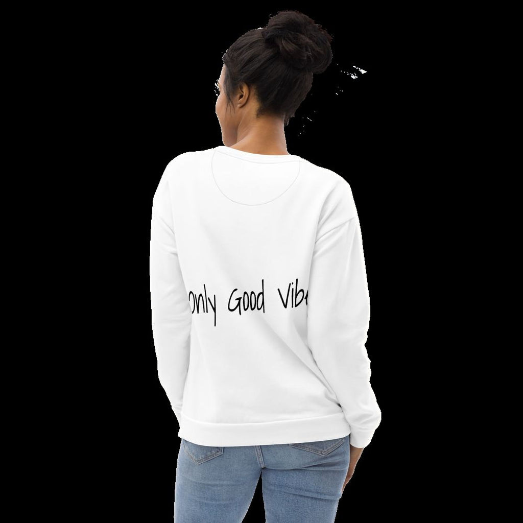 A woman wearing a white sweater with the text "Only Good Vibes" printed on it, standing against a black background.