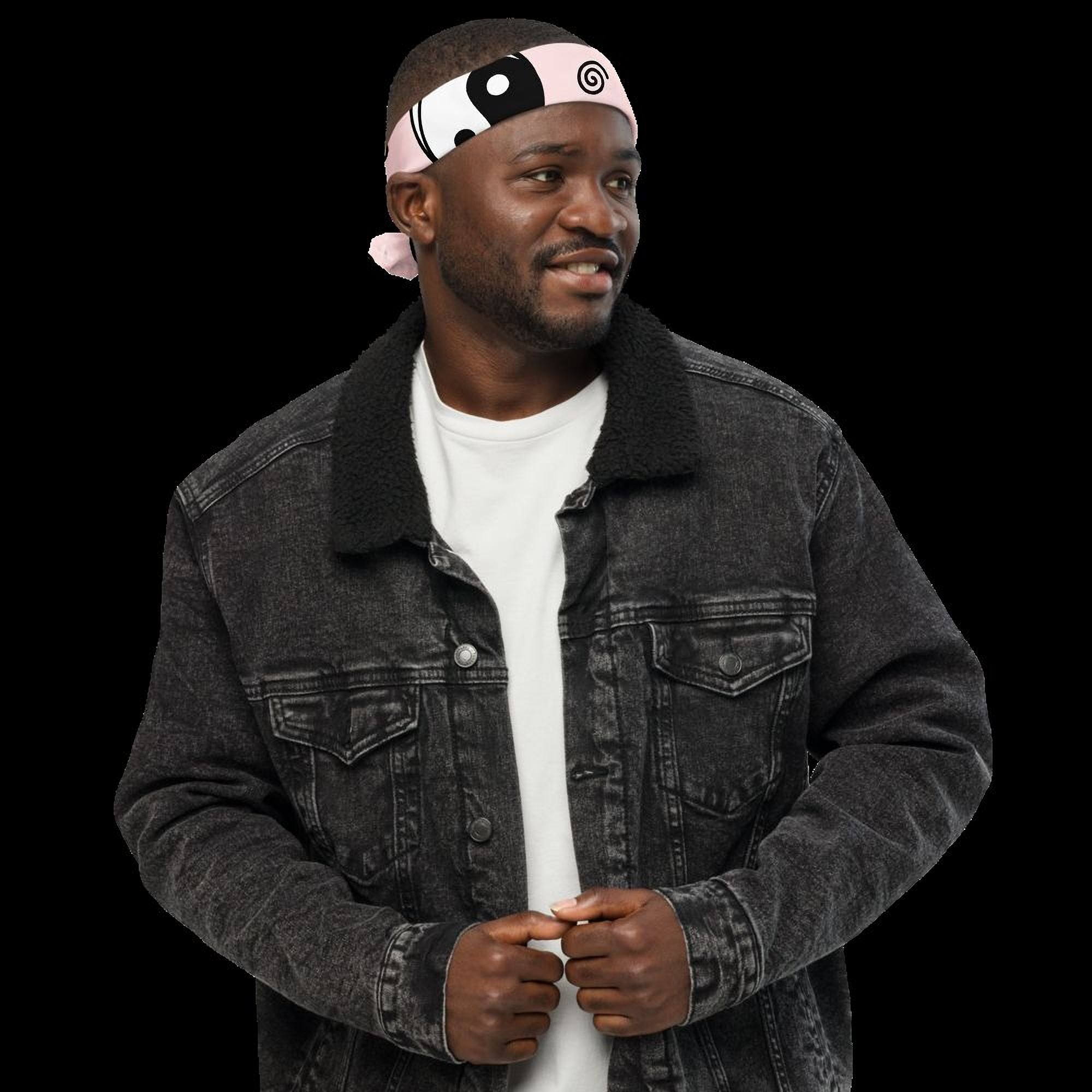 A man wearing a black denim jacket and a pink and black bandana stands against a black background.
