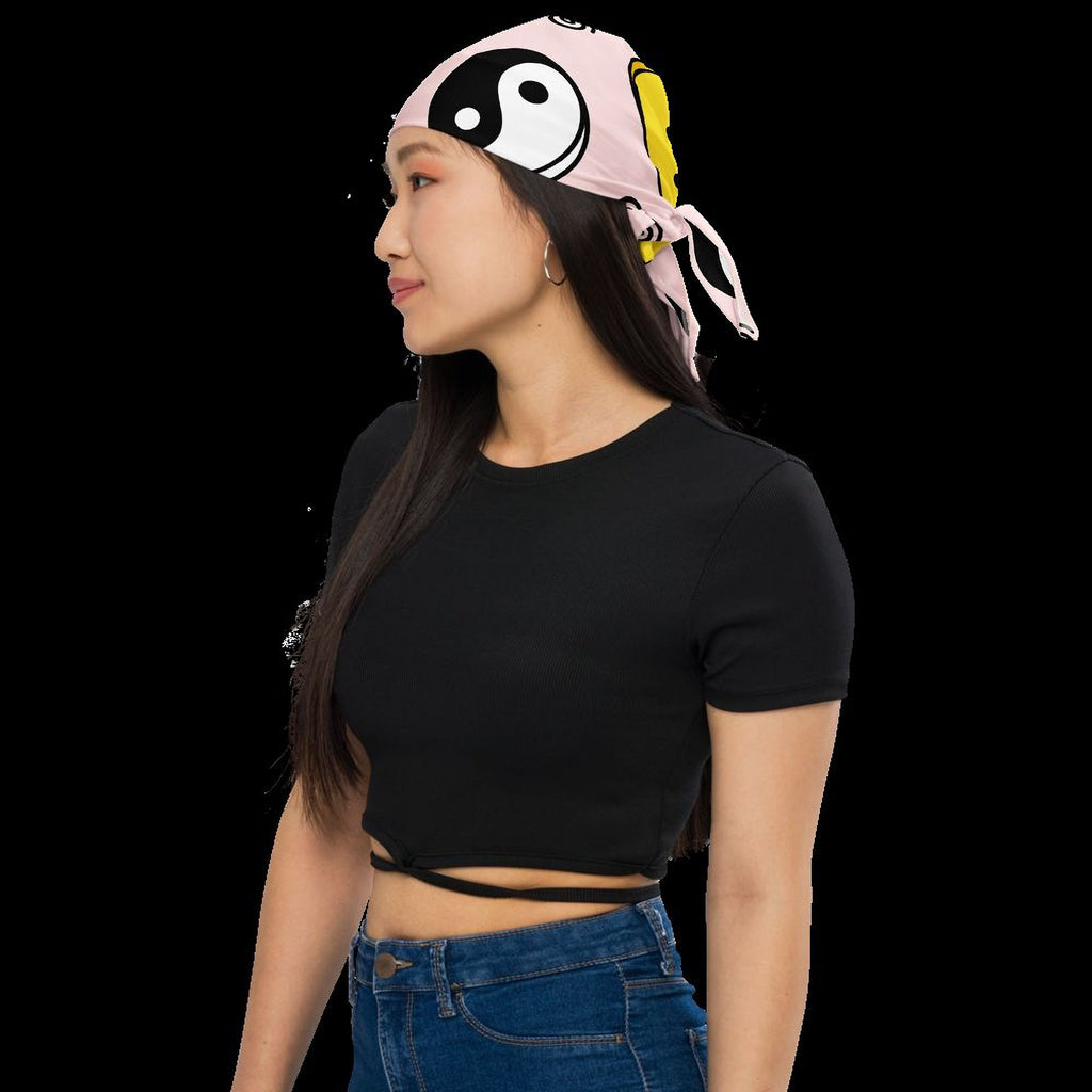 A woman wearing a black shirt and blue jeans, with a pink and yellow headband featuring a yin and yang symbol on her head.