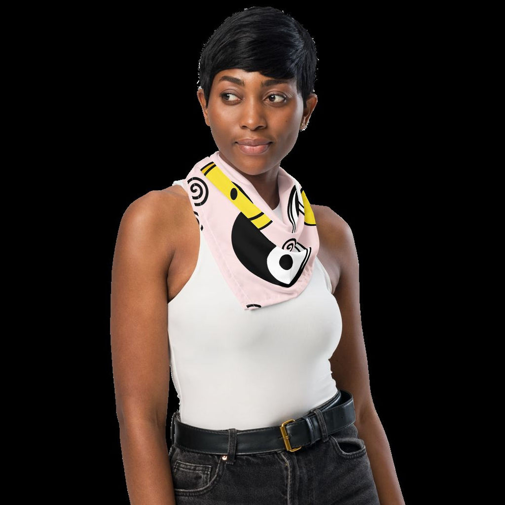 A woman with short hair wearing a white tank top and a colorful scarf stands against a black background.