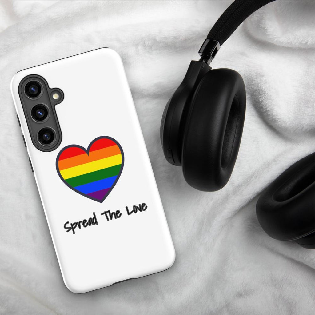A white phone case with a rainbow heart and the text "Spread The Love" printed on it, along with a pair of black headphones.