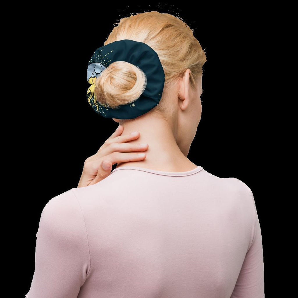 A woman with blonde hair is shown from behind, her hand resting on her neck. She is wearing a pink shirt and has a green hair accessory on her hair.